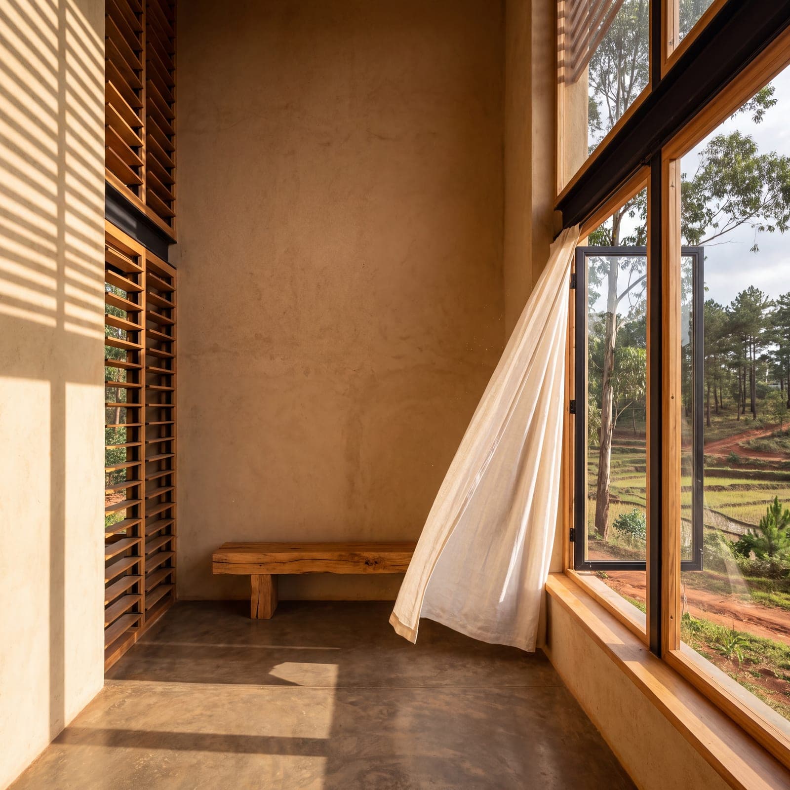 Room bathed in light, a curtain lifted by the breeze at a large open window